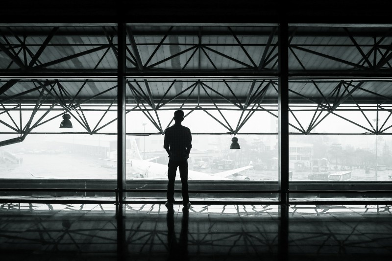man kijkt vanaf de rug naar buiten over een vliegveld