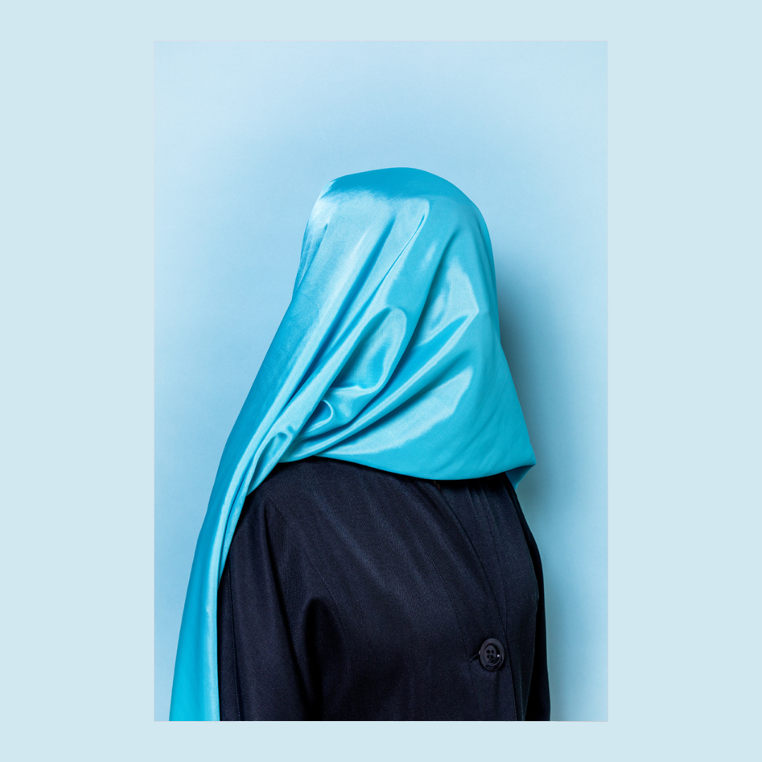 vrouw in zwart met blauwe sluier om hoofd, tegen blauwe achtergrond